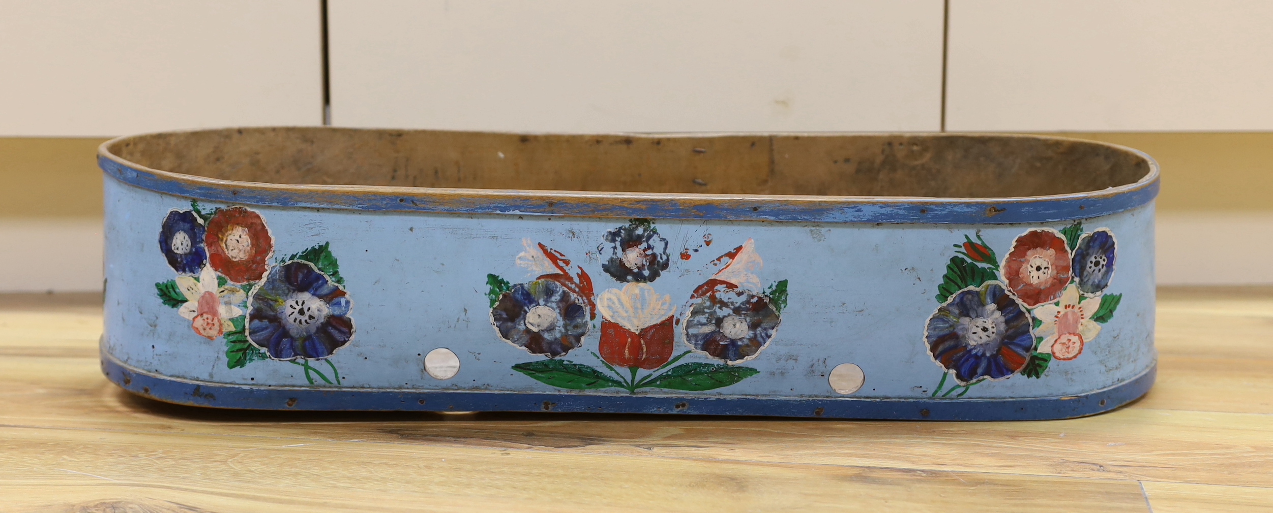 A 19th century Greek painted bentwood trough, decorated with multicoloured flowers on a mid blue background, 69cm wide, 15cm high